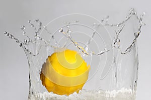 Lemon splashing into clear water on white background.