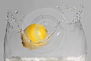 Lemon splashing into clear water on white background.