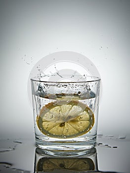 lemon splashing into a glass of water