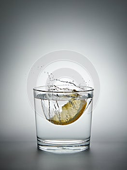 lemon splashing into a glass of water