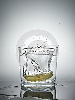 lemon splashing into a glass of water