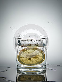 lemon splashing into a glass of water