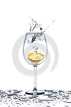 Lemon splashing into glass of water on white background