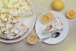 Lemon Tart with Meringue Caramelized Cream on plate on white wooden background and a piece of Tart with Lemon Fruits