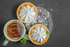 Lemon tart with mint leaves and a cup of cappuccino with chocolate topping