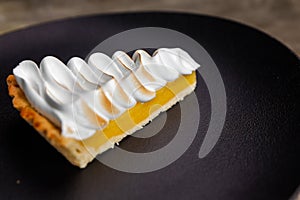 Lemon tart with protein cream on black plate