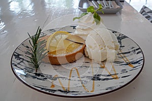 Lemon tart with vanilla ice cream on cute round plate in cafe