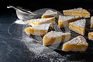 Lemon triangles with powdered sugar on a round cooling rack.