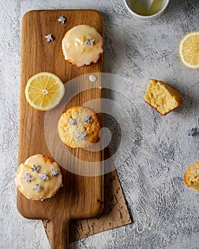Lemon yellow cupcakes on a wooden board, top view.