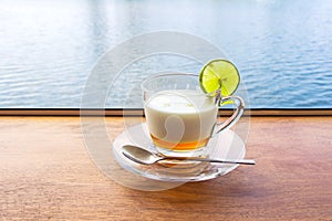 Lemon yogurt fresh milk in a clear glass placed on a brown wooden table with sea water surface background