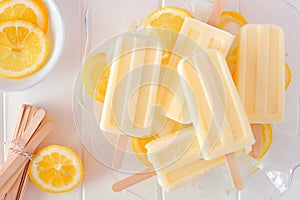 Lemon yogurt popsicles in a transparent bowl against white wood