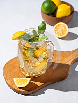 Lemonade drink or cold tea with fresh lemon, mint and ice in a jar. Refreshing citrus mojito cocktail on a wooden board on a