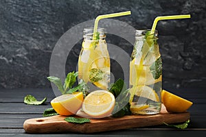 Lemonade drink of soda water, lemon and mint in jar on black background