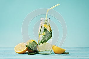 Lemonade drink of soda water, lemon and mint in jar on turquoise background