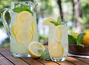 Lemonade in glass and pitcher with mint and sliced lemons