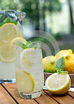 Lemonade in glass and pitcher with mint and sliced lemons