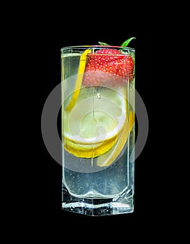 Lemonade in a high transparent glass on a black background, decorated with lemon slices and strawberries