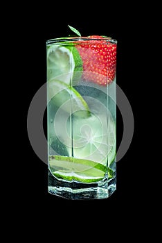 Lemonade in a high transparent glass on a black background, decorated with lime slices and strawberries