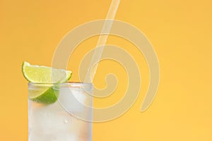 Lemonade with ice and lime on a bright orange background