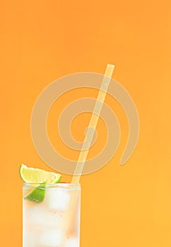 Lemonade with ice and lime on a bright orange background