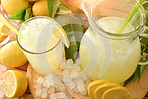 Lemonade with ice in pitcher and glass on wooden table