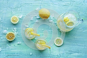 Lemonade. Lemon water drink with ice. Two glasses and a pitcher on blue