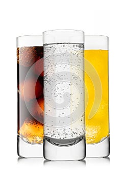 Lemonade soft drink with cola and orange soda with ice cubes in highball glasses on white background