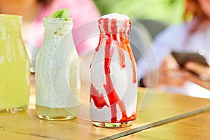 Lemonade, strawberry and kiwi milkshake on wooden table in front of woman