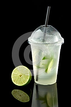 Lemonade to go cup with mint, lime and kiwi on black background, isolated