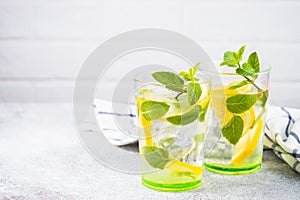 Lemonade in two glasses at white table.