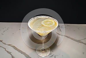 Lemondrop Martini on a white marble countertop with a blacked out background