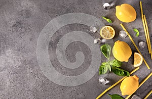 Lemons,  Basil sprigs, ice cubes, yellow and blue tubes on a gray background  top view