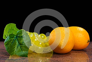 Lemons and a bunch of grapes on granite surface and black background