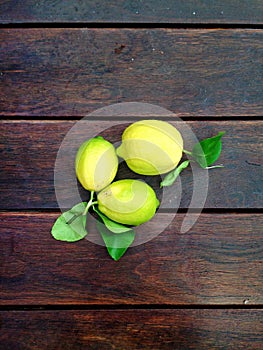 Lemons with leaves on surface of wooden table, seen from the above