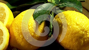 Lemons with leaves under drops water on wooden table