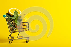 Lemons and mint in a small toy cart on a banana yellow background. online shop delivery concept. horizontal view