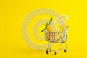 Lemons and mint in a small toy cart on a banana yellow background. online shop delivery concept. horizontal view