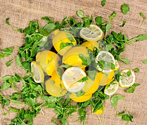 Lemons - sliced and full with green salad on canvas - top view