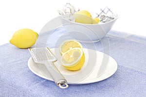 Lemons and zester on a white plate