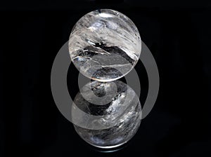 Lemurian Clear Quartz Sphere crystal magical orb isolated on a black mirror background