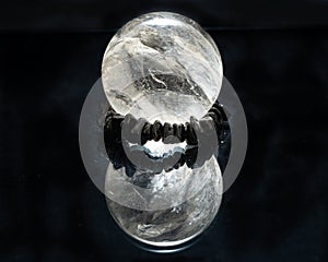 Lemurian Clear Quartz Sphere crystal magical orb isolated on a black mirror background