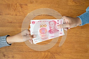 Lend or Giving money concept. Top view hand giving banknote currency Chinese Yuan (CNY or RMB photo