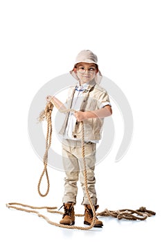 Length view of explorer kid in hat and glasses holding rope on white