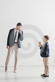 Length view of father and son in jackets with boutonnieres looking at each other