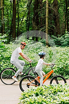 Length view of father and son riding bicycles while dad looking at boy bicycle wheel