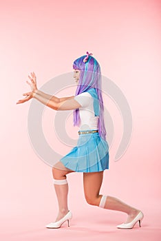 Length view of smiling otaku girl in purple wig posing on pink