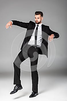 Length view of zombie businessman in black suit on grey