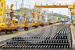 Lengths of rail stacked along track mounted cranes at depo