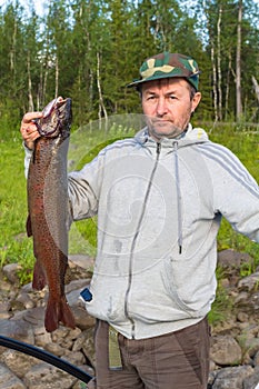Lenok - siberian trout. Fisherman with a prey. Krasnoyarsk Territory, Russia.