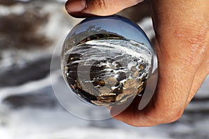 Through lens ball watchs rough sea, tides and foamed water as it smashes against the rocks. Piece of famous beach Baths Of